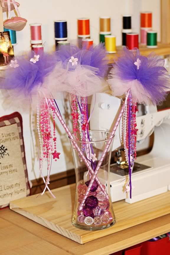 two vases filled with purple and pink flowers on top of a wooden table next to sewing machines