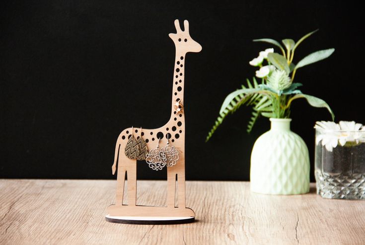 a wooden giraffe standing next to a potted plant on a wood table