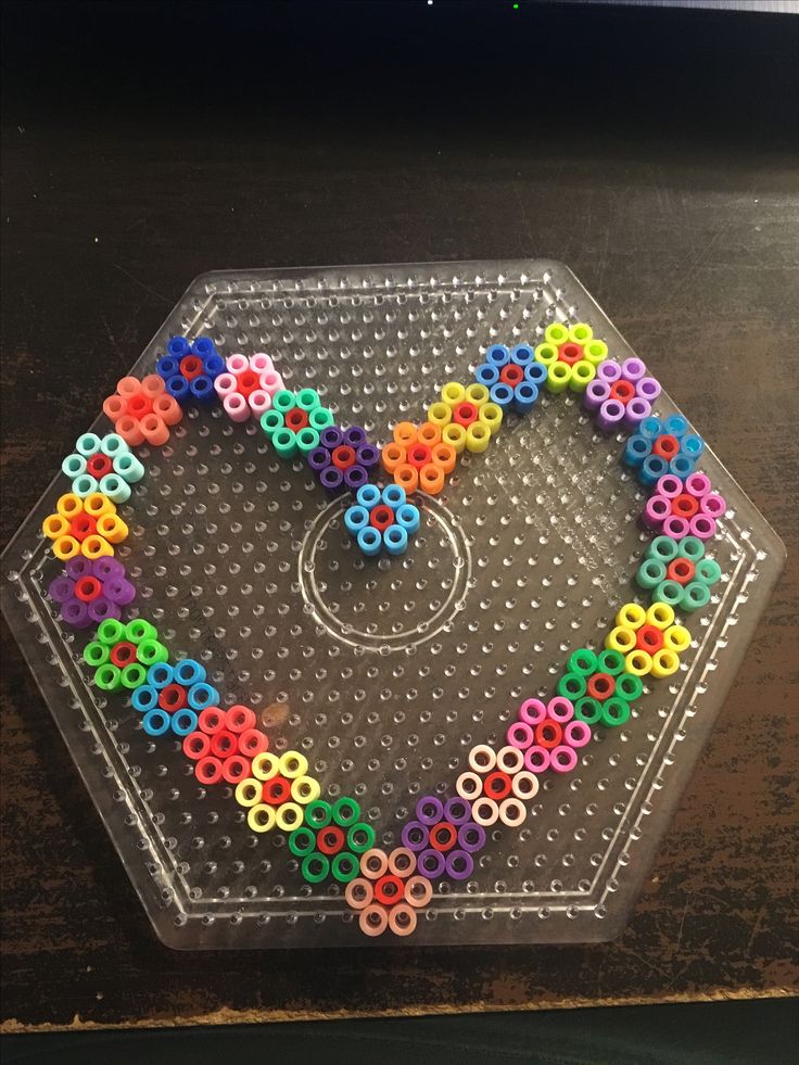 a plastic tray with colorful beads arranged in the shape of a heart on top of it