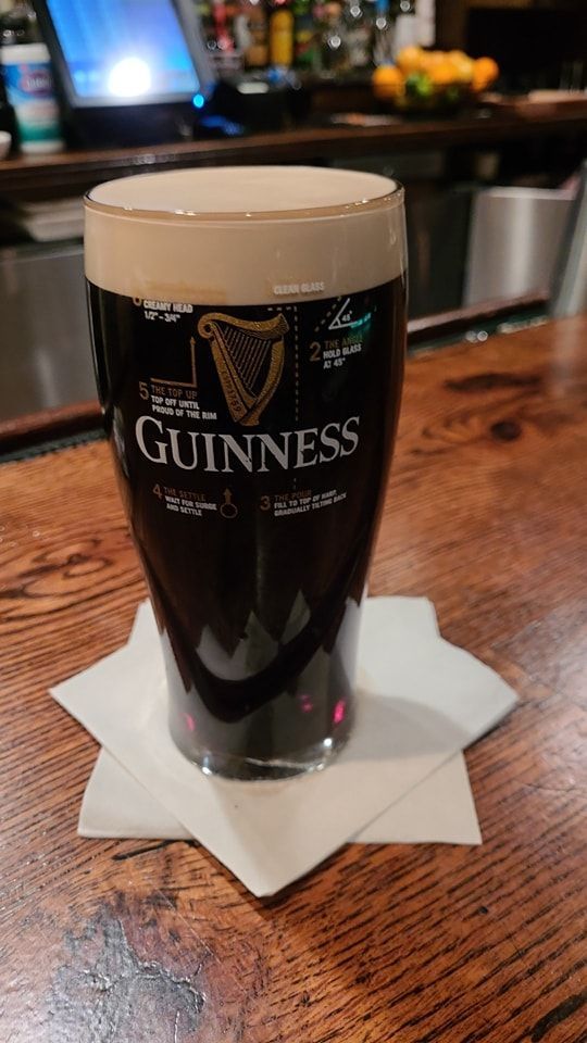 a glass of guinness sitting on top of a wooden table