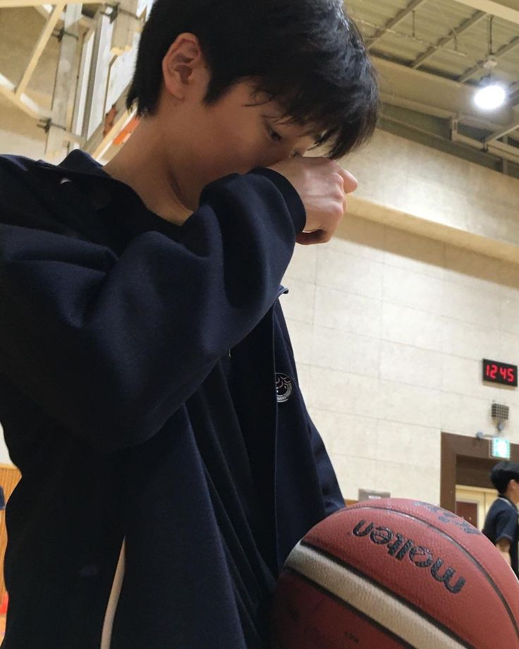 a young man holding a basketball in his right hand while standing next to a ball