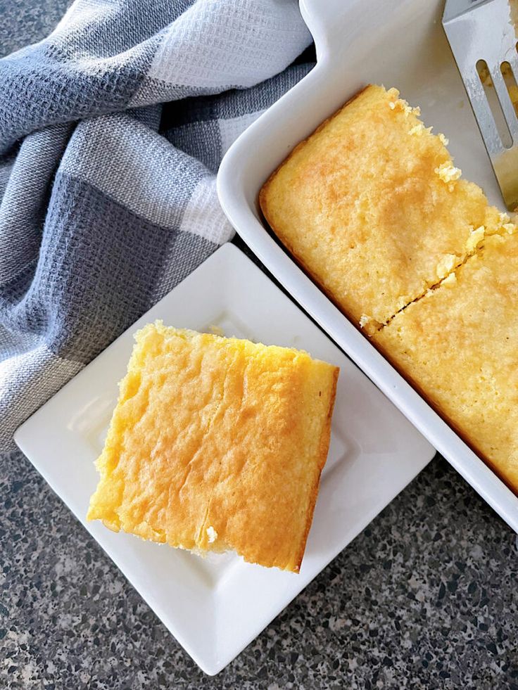 a white plate topped with a piece of cake next to a pan filled with it