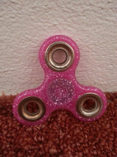 a pink fidget toy sitting on top of a brown carpet next to a white wall