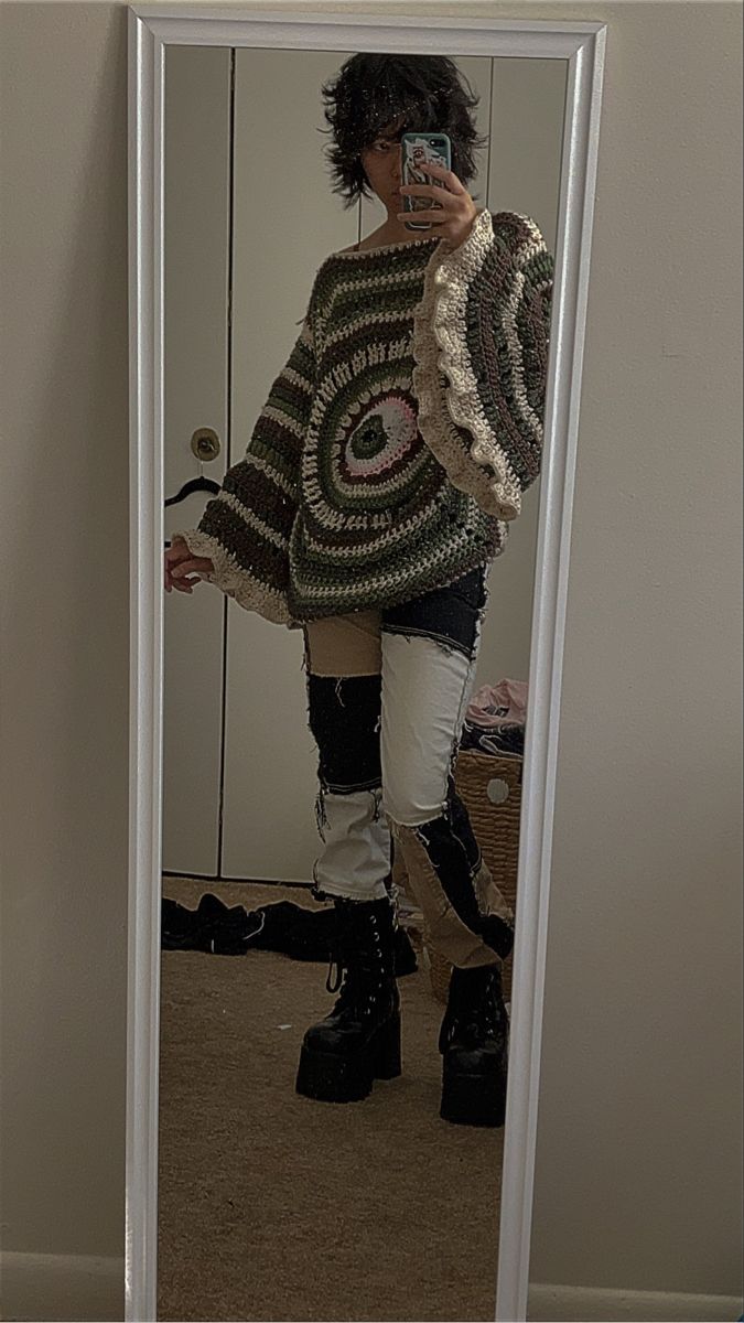 a woman taking a selfie in front of a mirror wearing boots and a sweater