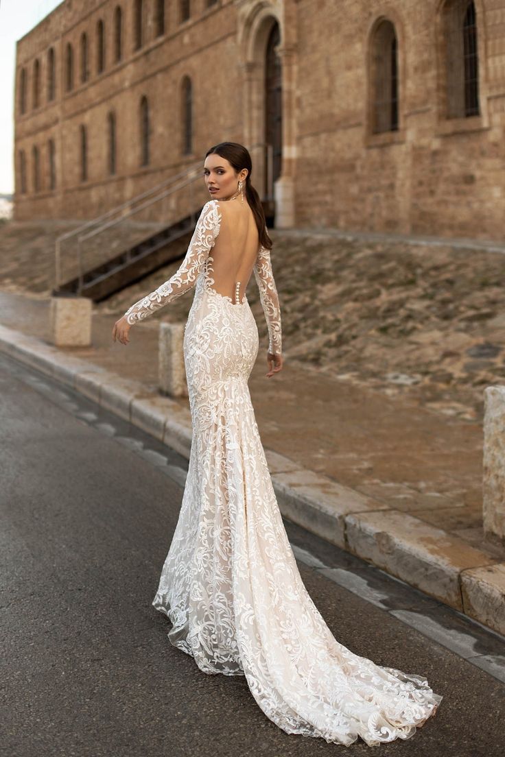 a woman in a wedding dress is walking down the street with her back to the camera