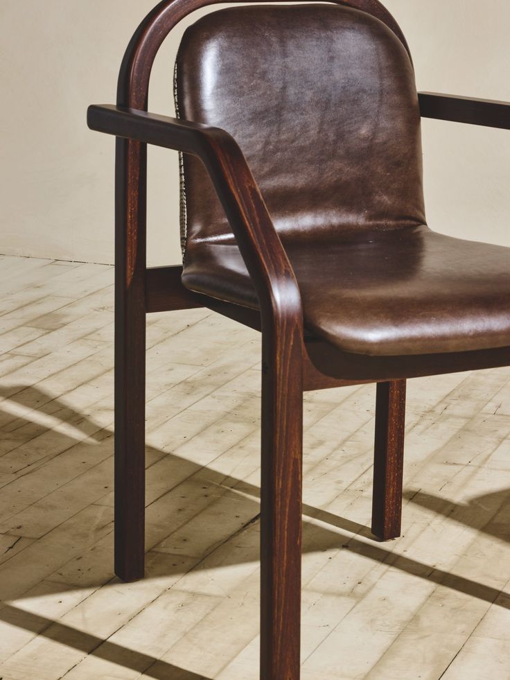 a brown leather chair sitting on top of a hard wood floor