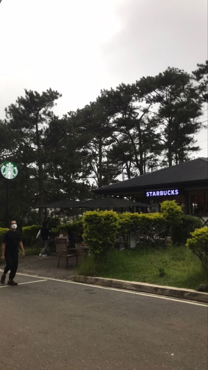 a man riding a skateboard down the middle of a street next to a starbucks