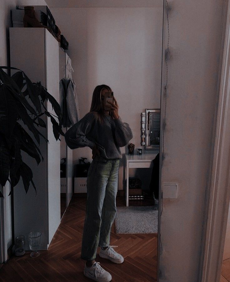 a woman standing in front of a mirror with her hands on her hips and looking at herself