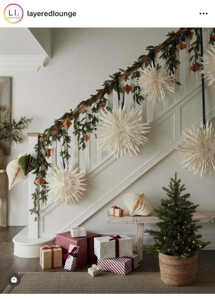 christmas decorations and presents under the banister in this home decorated with greenery, snowflakes and starbursts