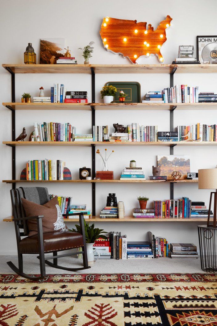 a living room filled with lots of furniture and bookshelves next to a rug