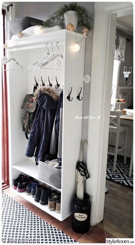 a white coat rack with shoes and coats hanging on it's sides, in front of a dining room table