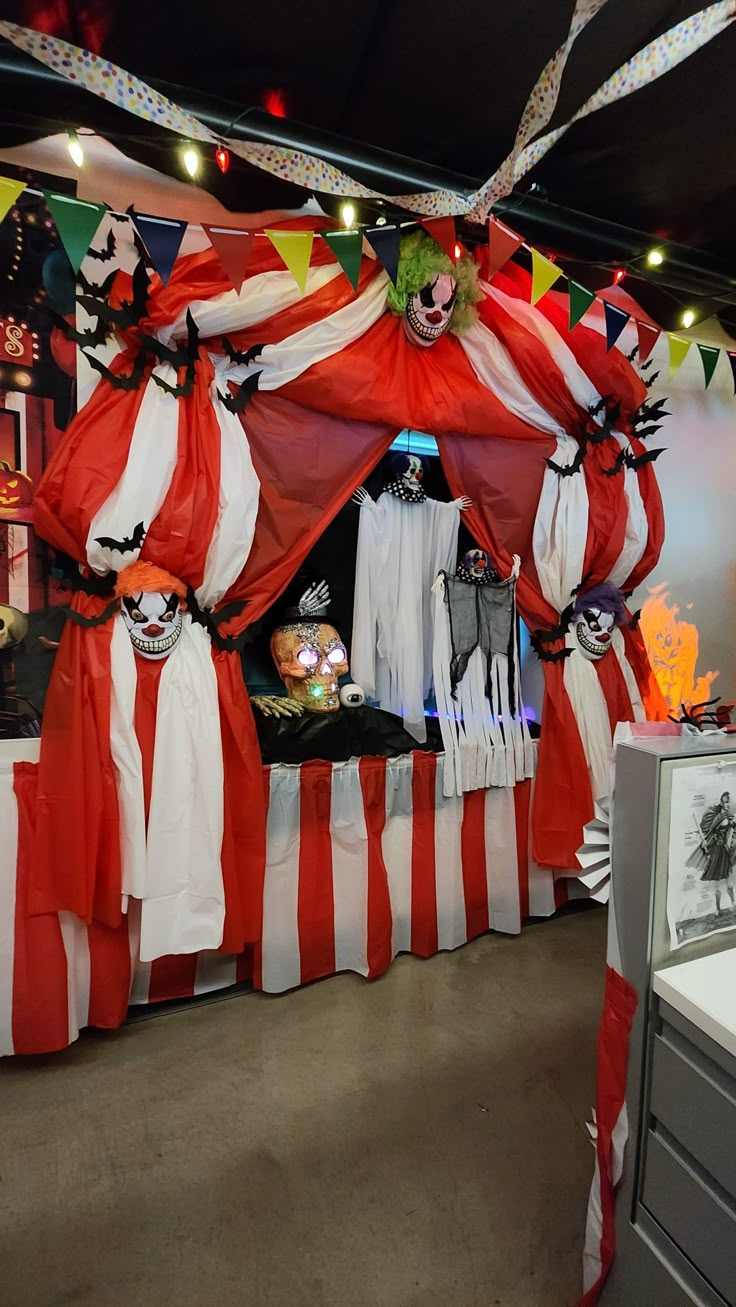 a bed covered in red and white drapes with clowns on it's sides