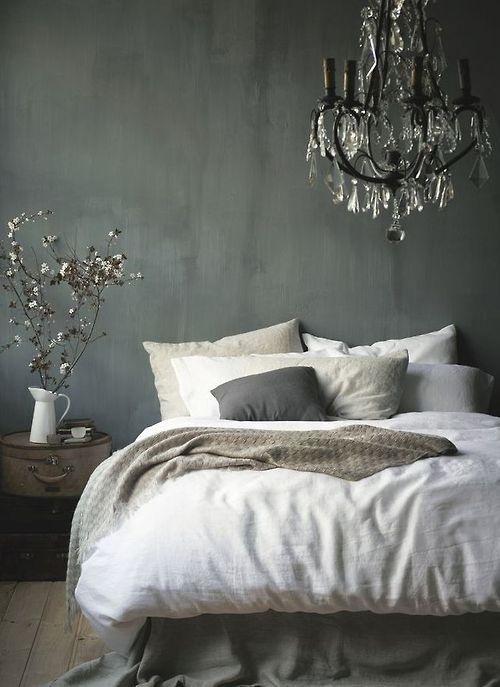 a bedroom with a chandelier hanging from the ceiling and a bed in front of it