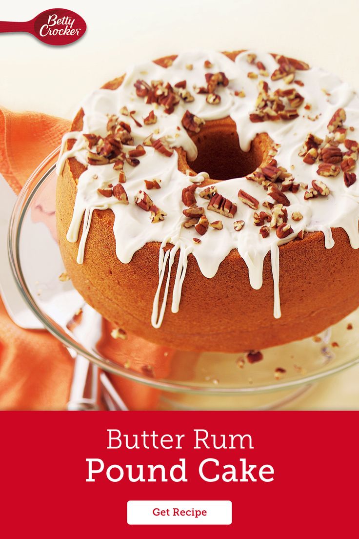 a bundt cake with white icing and pecans on top is sitting on a glass plate