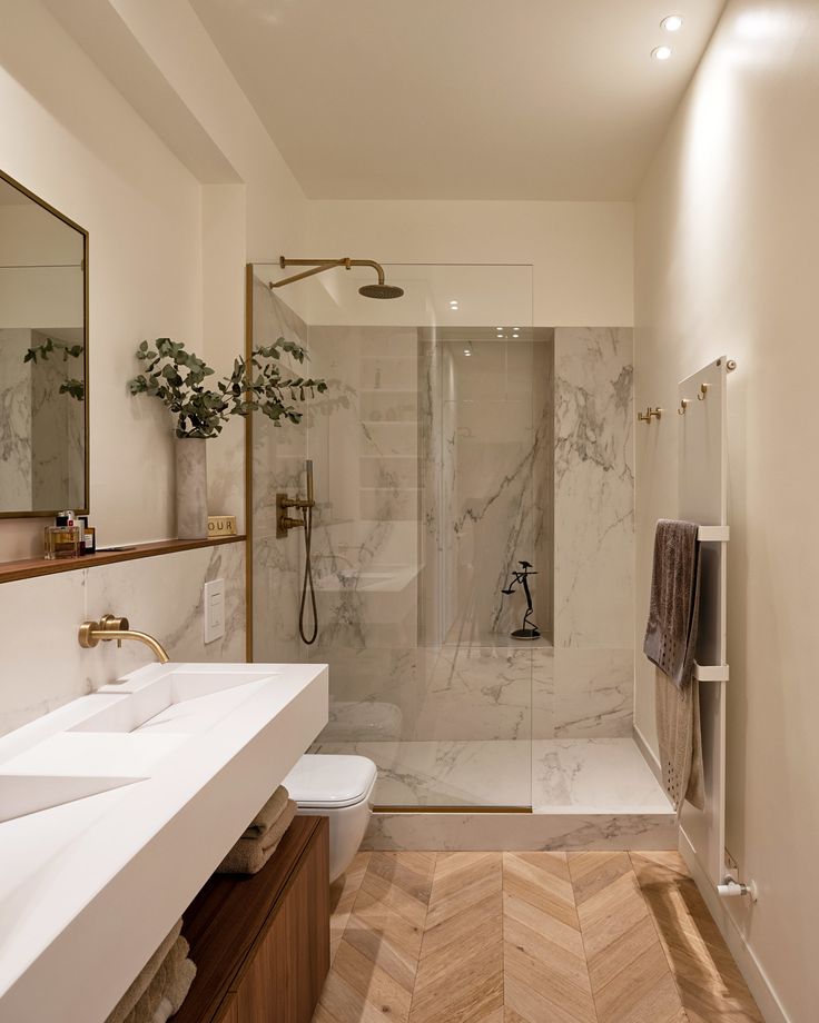 a bathroom with a walk in shower next to two sinks and a large mirror on the wall