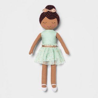 a doll with brown hair wearing a light green dress and white shoes, sitting on a white surface