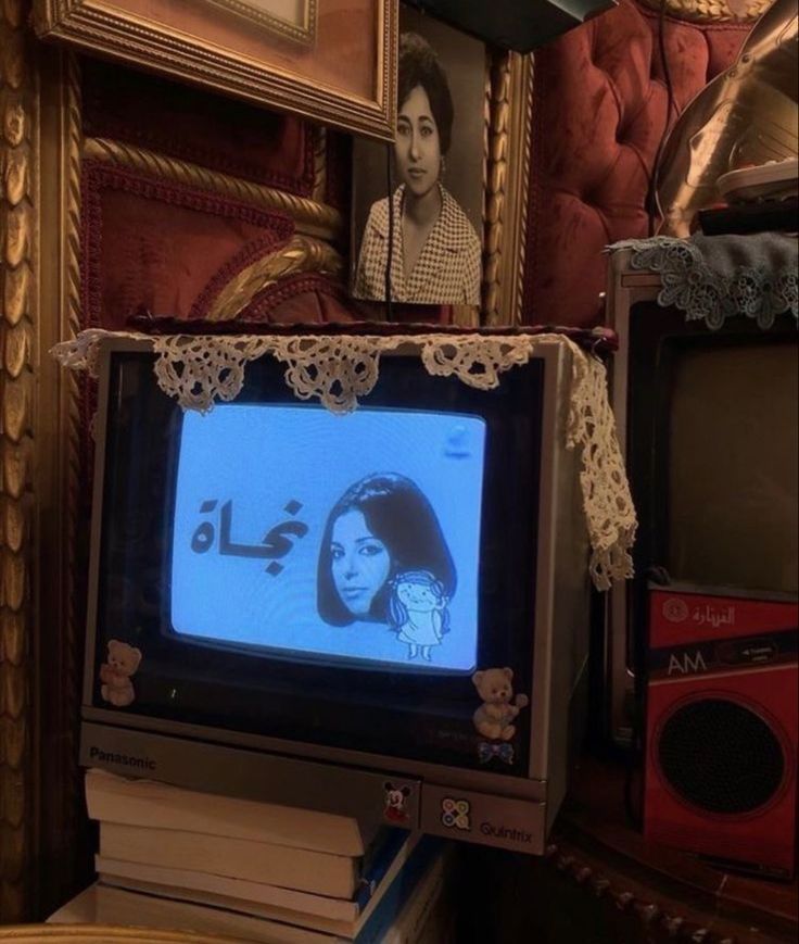 a tv sitting on top of a table next to a pile of books and pictures