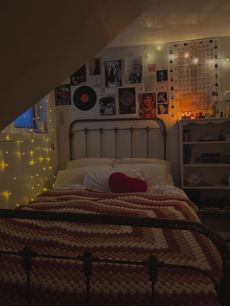 a bed in a room with lights on the wall and pictures above it, along with bookshelves