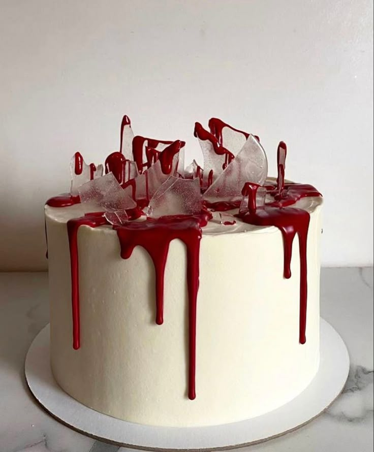 a white cake with red icing dripping down the side and on top of it