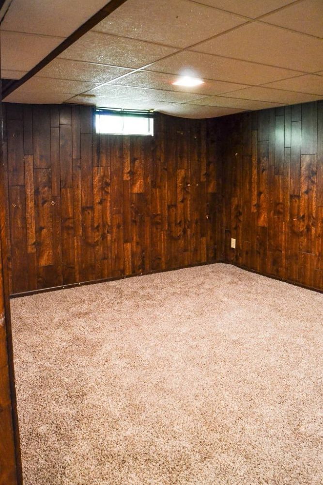 an empty room with wood paneling and carpeted walls in the corner is shown