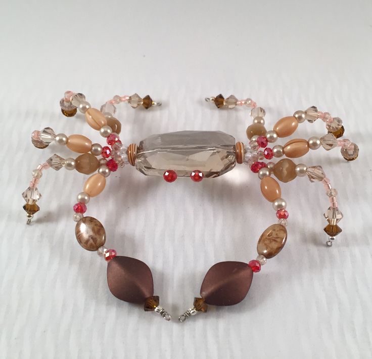 a beaded bracelet with glass beads and charms on it's sides, sitting on a white surface