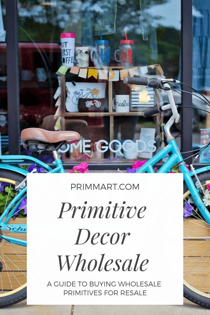 a blue bicycle parked in front of a store window with the words primitive decor wholesale on it