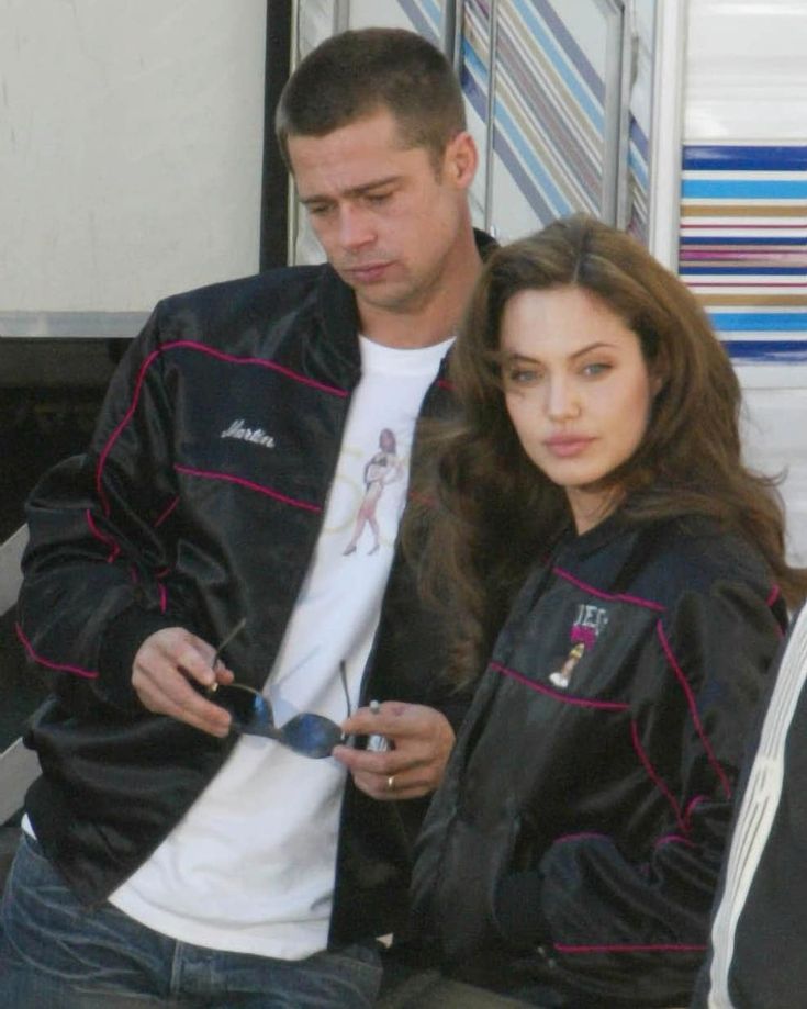 a man and woman standing next to each other looking at their cell phones in front of a truck