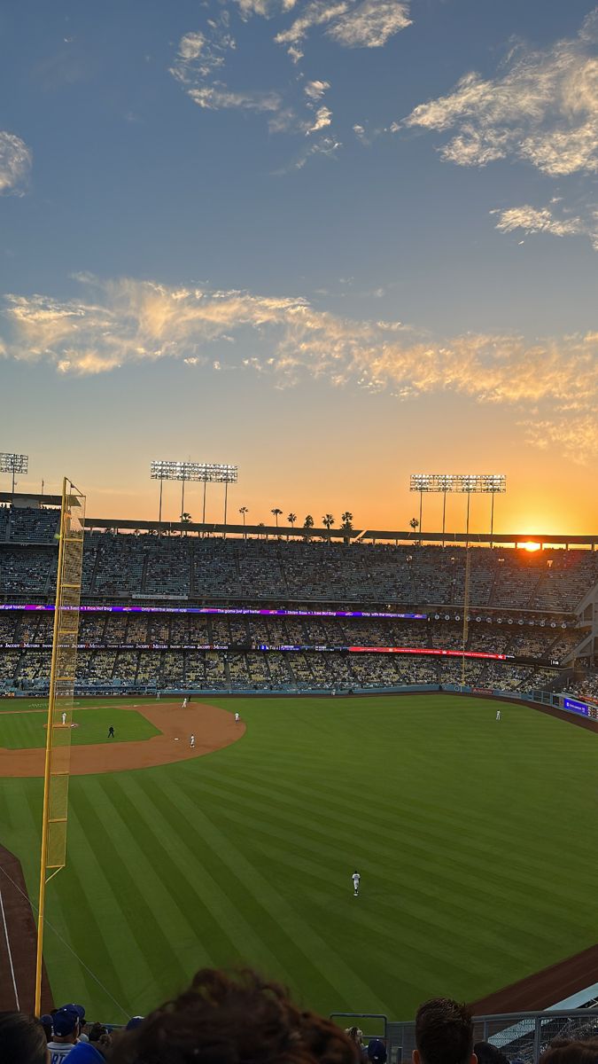 the sun is setting over a baseball field