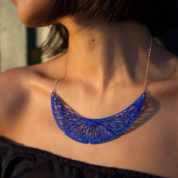 a woman wearing a blue necklace with an intricate design on the back of her neck