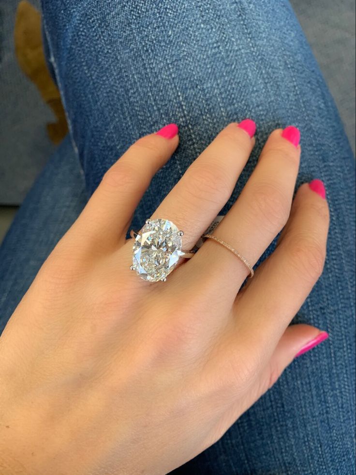 a woman's hand with pink nails and a ring on her left hand, wearing blue jeans