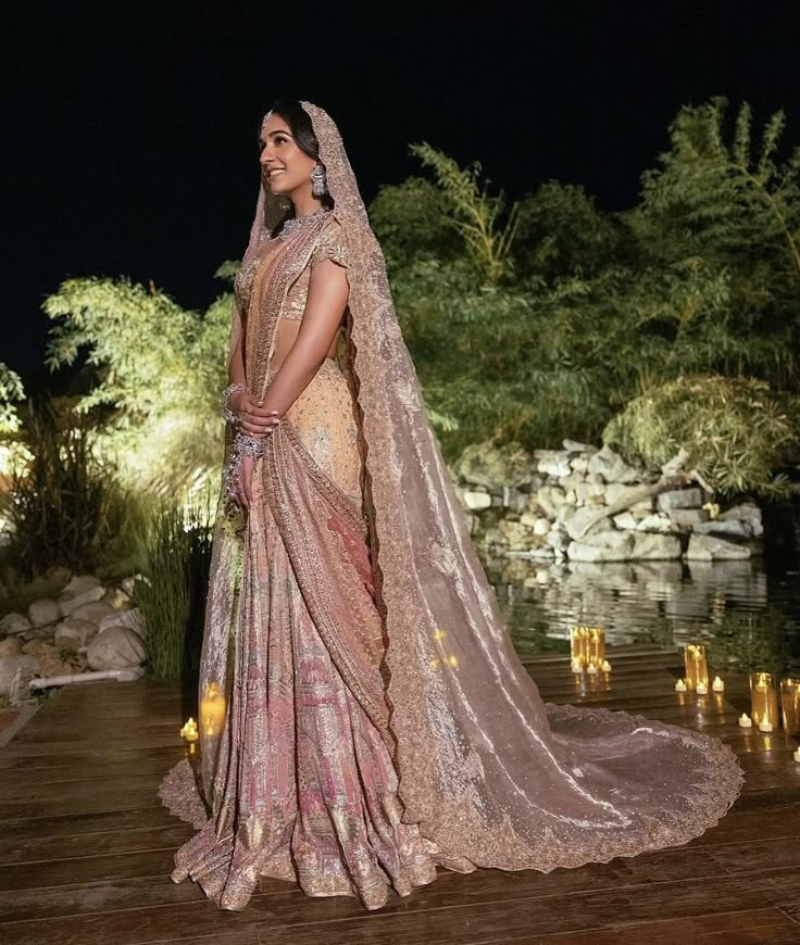 a woman in a bridal gown standing on a wooden platform with candles around her