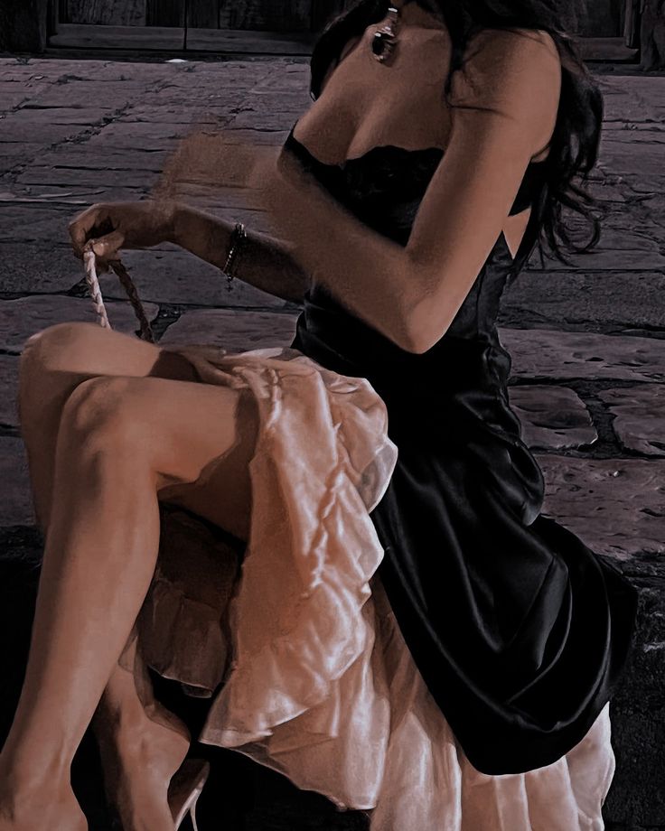 a woman in a black dress sitting on a bench