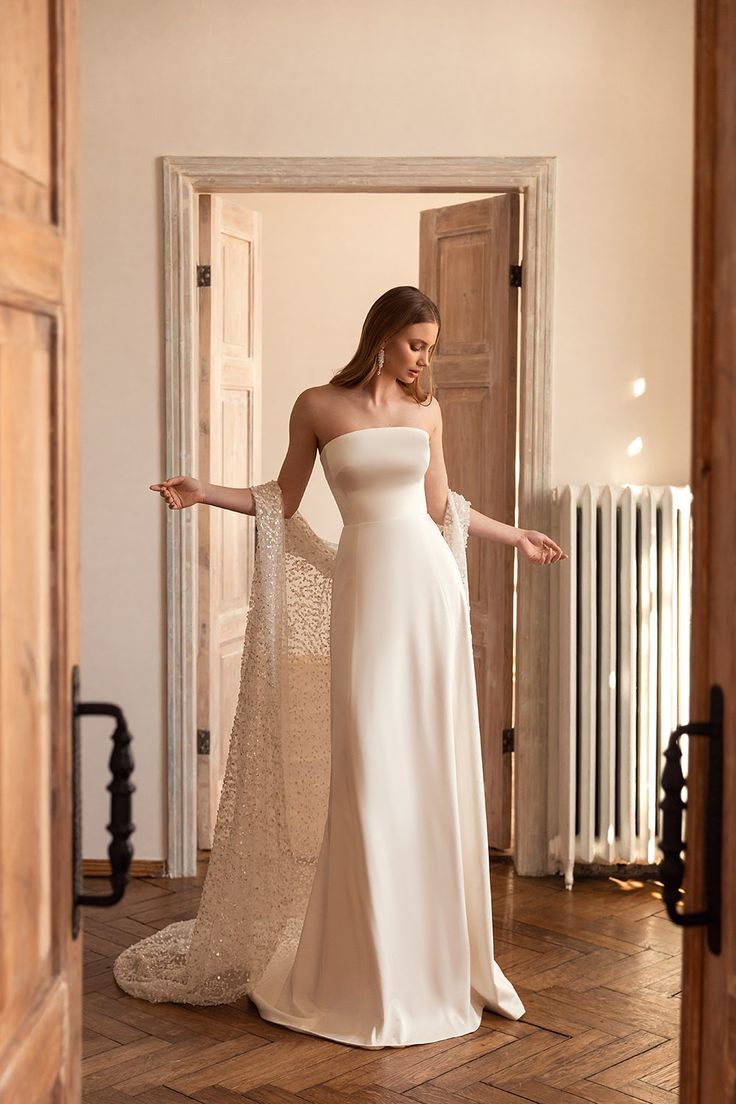 a woman in a white dress is standing on the floor with her arms spread out