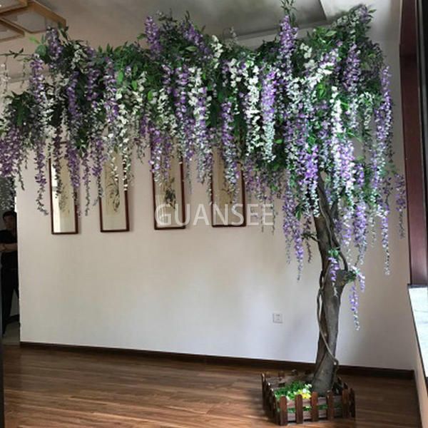 purple and white flowers are growing on the wall next to a tree in a room