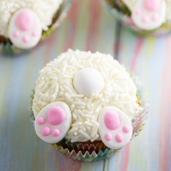 some cupcakes with white frosting and pink paws on top are sitting on a table