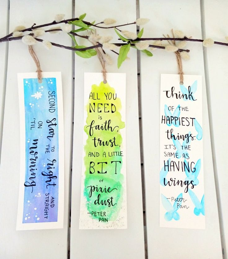 three watercolor bookmarks with bible verses on them hanging from a twig