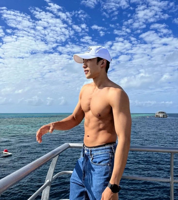 a shirtless man standing on the deck of a boat