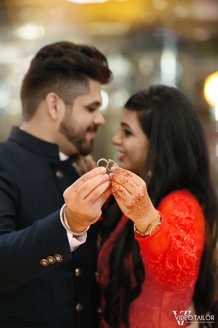 a man and woman standing next to each other holding rings