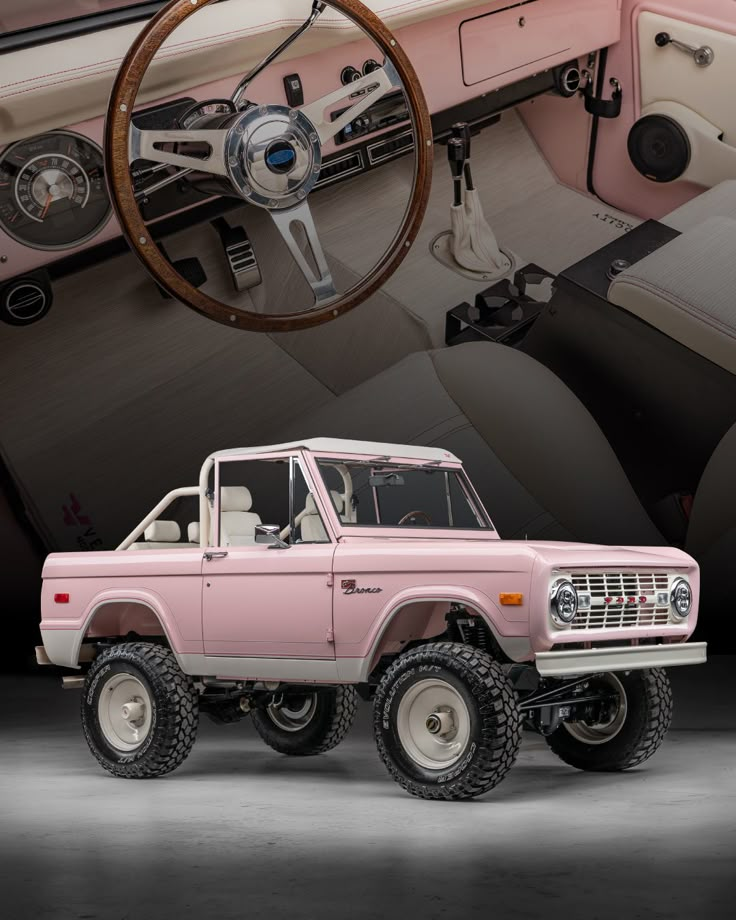 an old pink truck is parked in front of the steering wheel