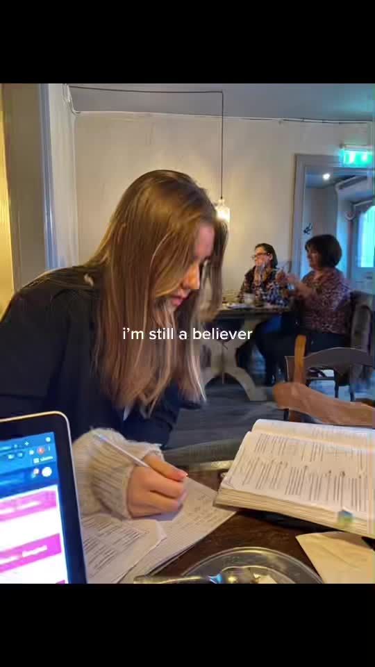 a woman sitting at a table writing in a book