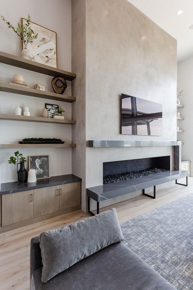 a living room with a couch, fireplace and shelves on the wall in front of it