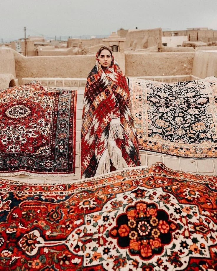 a woman standing on top of a pile of rugs