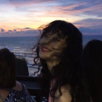 two women standing next to each other in front of the ocean at sunset or dawn