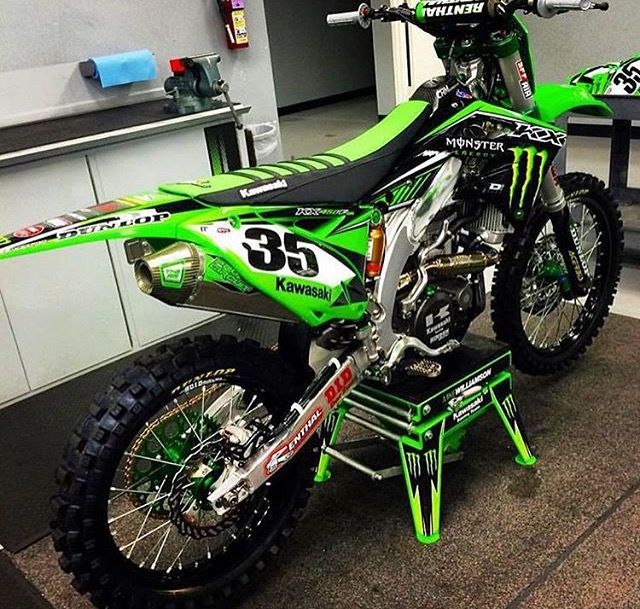 a green and black dirt bike sitting on top of a table in a room with white walls