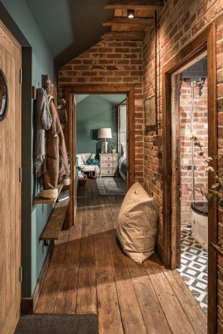 a hallway with wooden flooring and brick walls, along with an entry way leading to the bedroom