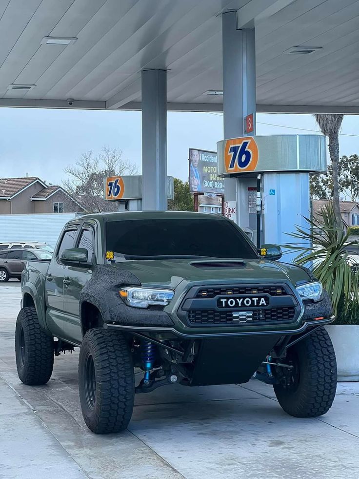 a green truck parked in front of a gas station with the number 76 on it