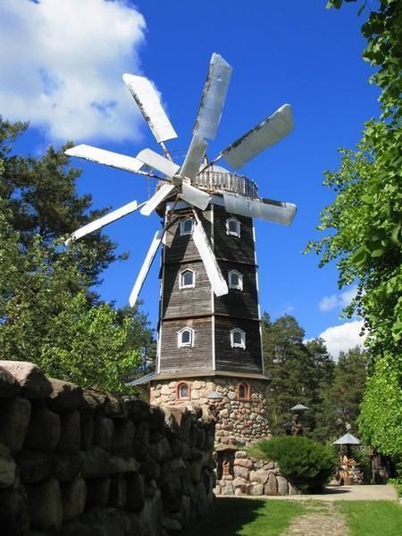 a windmill is shown in the middle of a grassy area next to a stone wall