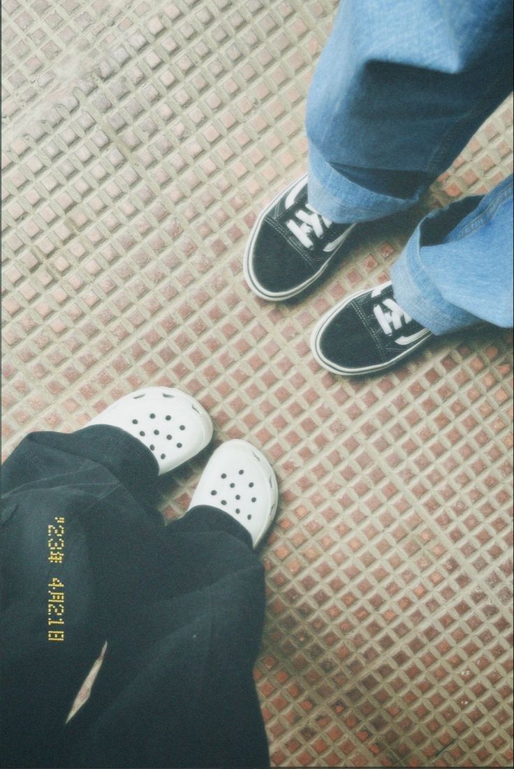 two people standing next to each other with shoes on the ground in front of them