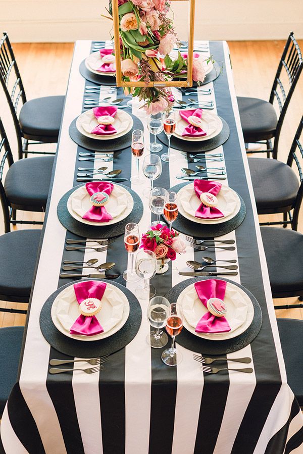 the table is set with black and white striped cloths, pink napkins, and silverware