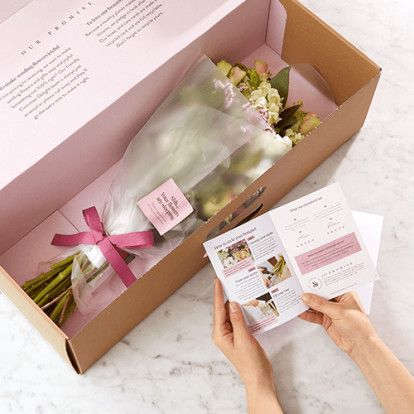 someone is opening up a pink box with flowers in it and instructions on how to wrap the package